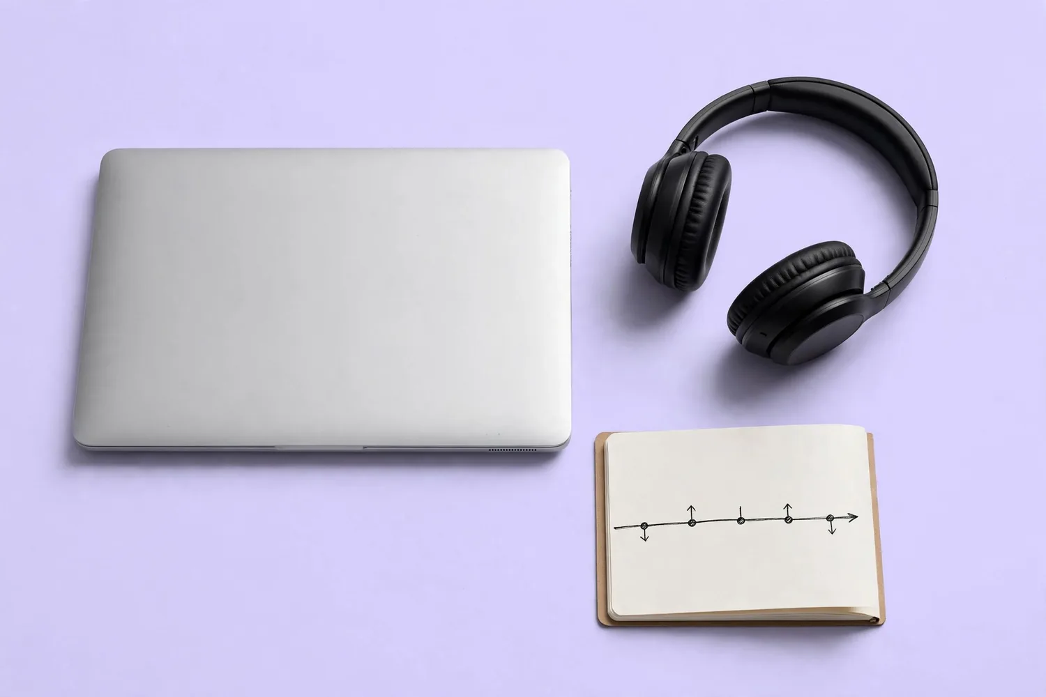 A laptop, headphones and a notebook